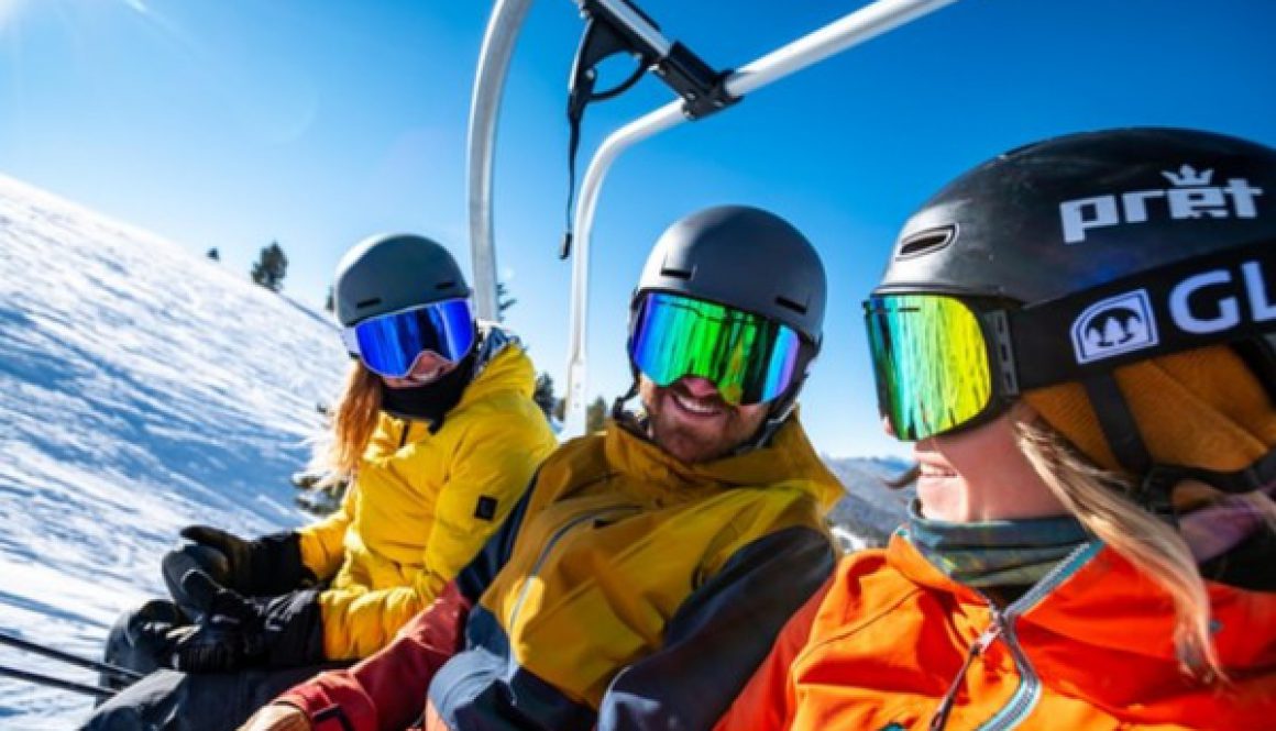 3 skiers sitting on a chairlift laughing at each other