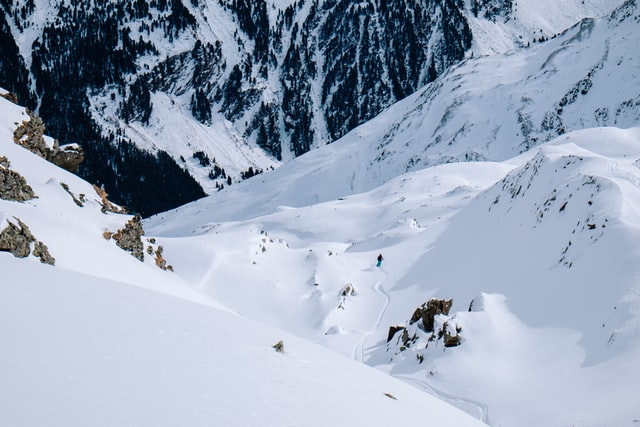 A solo skier skiing off piste through a mountain valley in Austria