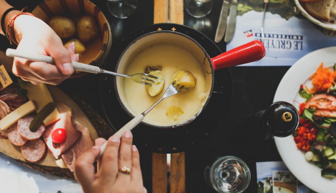 2 people dipping potatoes into a cheese fondue