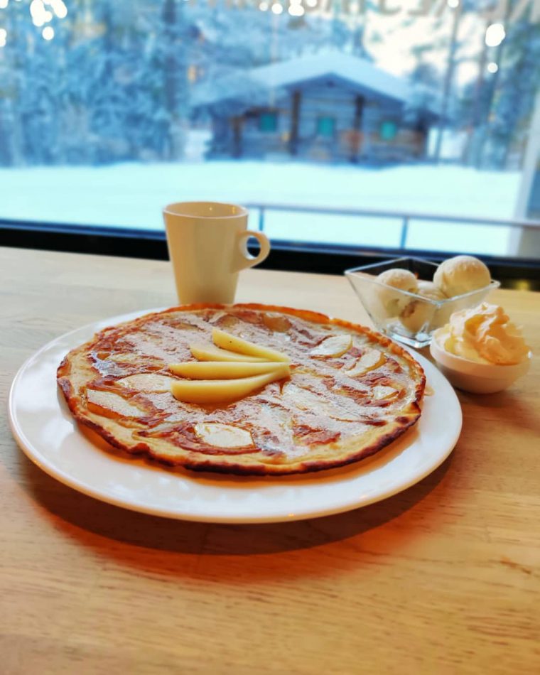 Sweet pancake covered with pears and syrup, next to a window