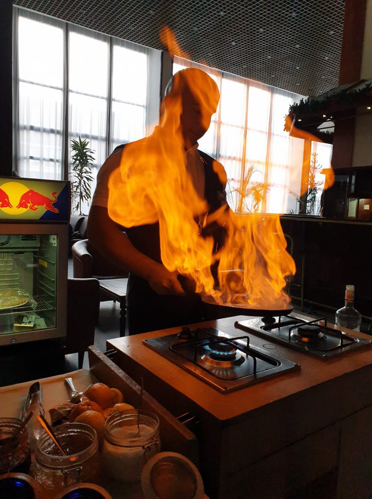 Man frying a pancake with flames coming from the pan