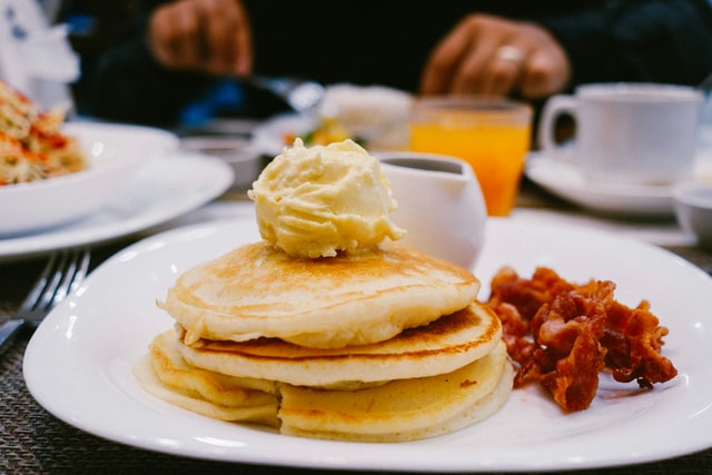 Stack of small & thick pancakes with rashers of bacon on the side 