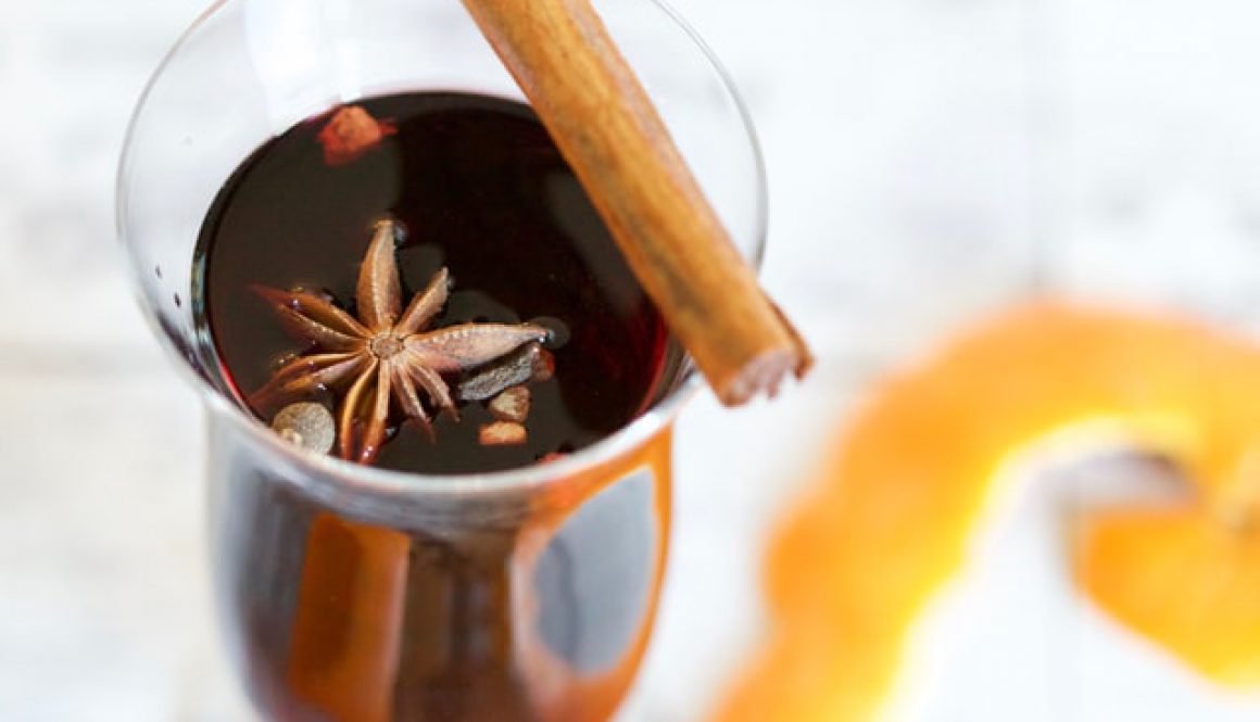 Close up of a glass of mulled wine with a star of cloves sitting at the top of the drink