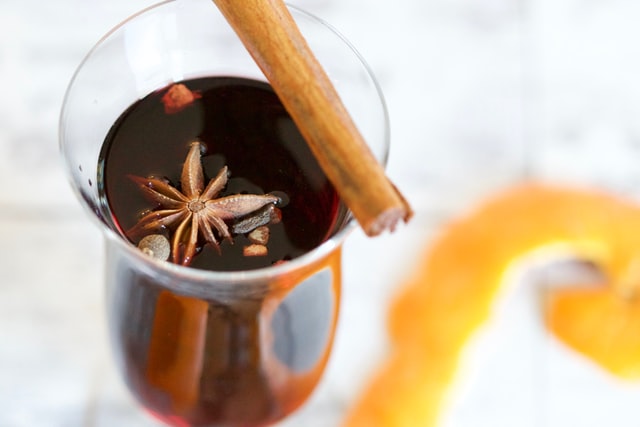 A small glass of mulled wine garnished with star anise and a cinnamon stick