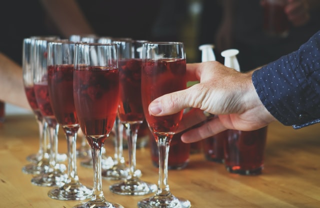 Champagne glasses lined up on a table filled with a pink drink and berries
