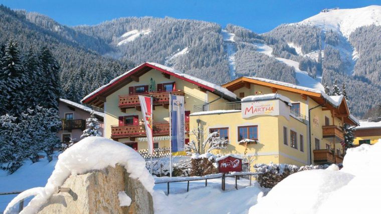 A yellow building with sloping roof surrounded by snowy mountains