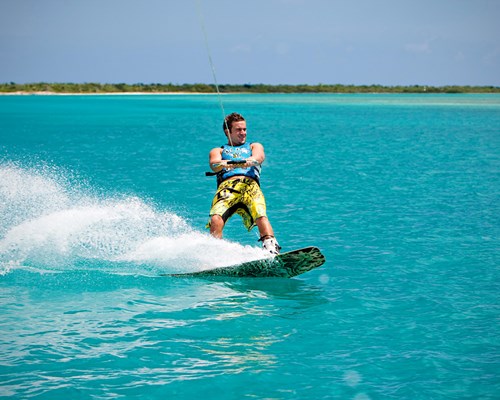 Man wakeboarding on a bright blue sea in a tropical destination