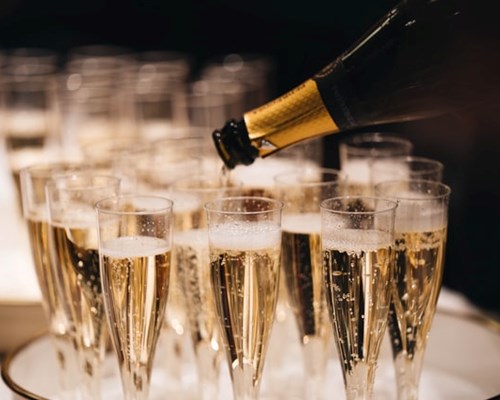 Full glasses of champagne on a tray with a bottle pouring champagne into a glass 