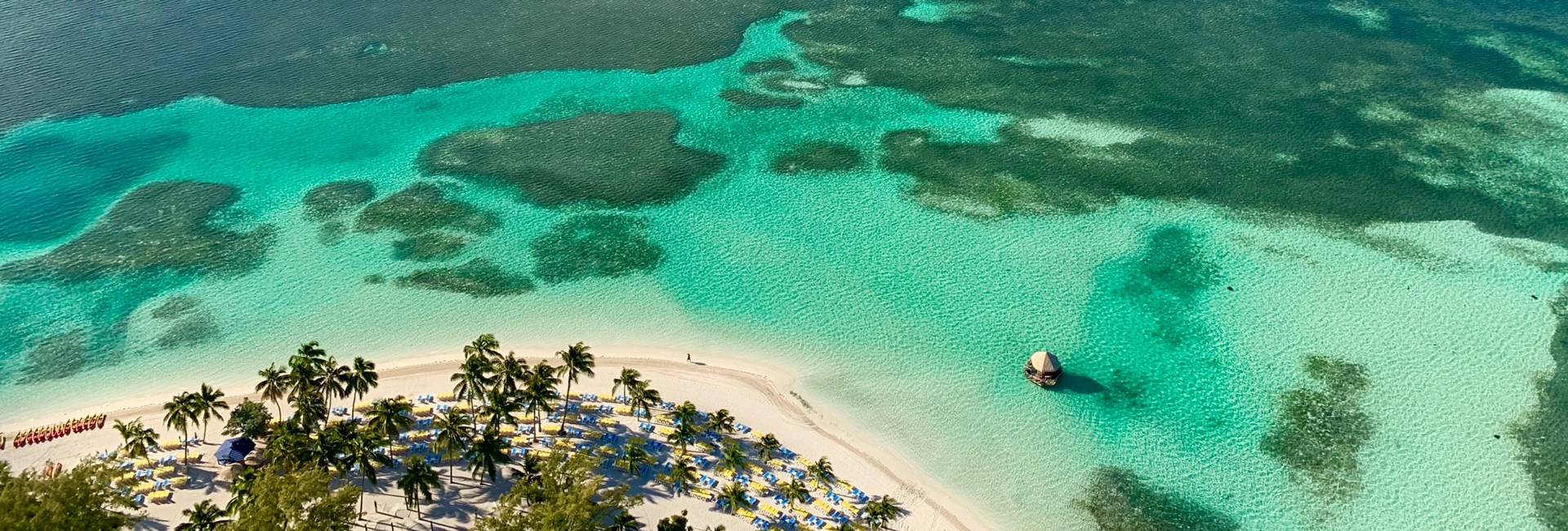 Aerial photo of an edge of a tropical white sand beach and clear turquoise sea