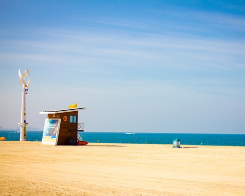 A small beach shack and turbines on a golden beach in Dubai