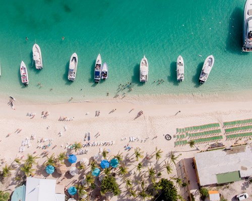 Yachts anchored on busy white sand beach in BVI - White Bay