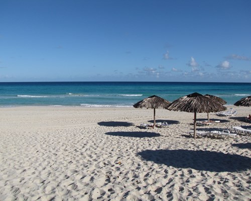Straw parasols and white sun loungers on a white sand beach