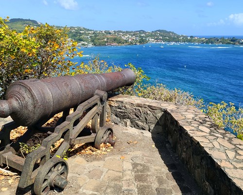 Old cannon on a cliff overlooking a bright blue sea