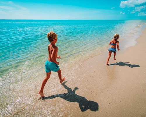 Happy young boy and girl running on a tropical beach 
