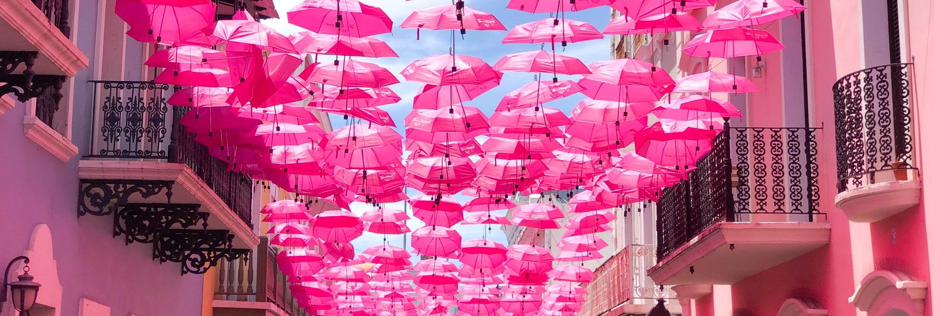 Pink umbrellas hanging over a street in San Juan