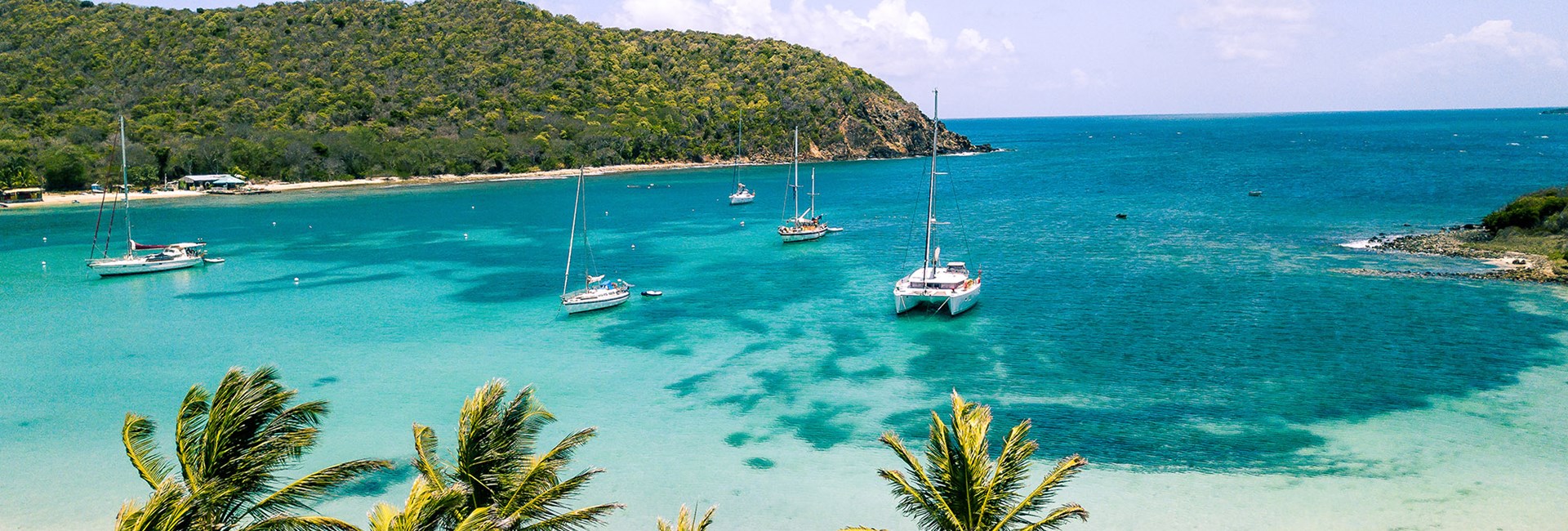 Aerial view of white sand Caribbean beach with sailing boats docked in the bay