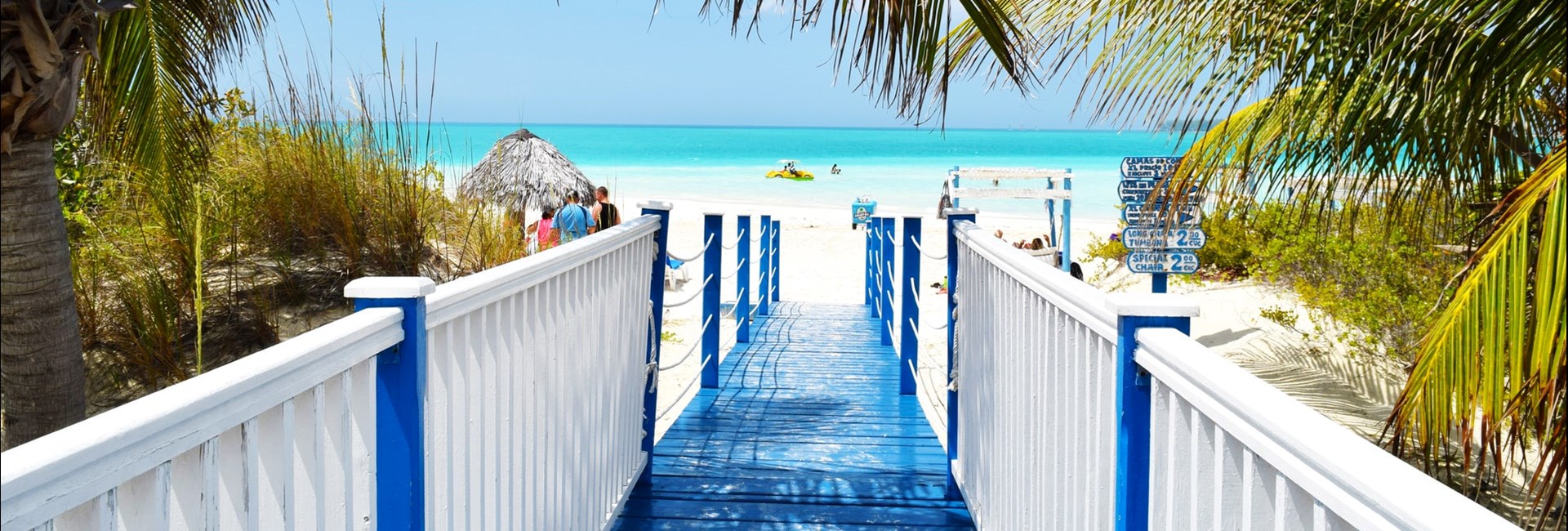 Blue and white bridge leading to a white sand tropical beach In Cuba 