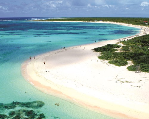 Aerial shot of curved white sand and blue waters with green vegetation beyond shoreline - Loblolly Bay, Anegada 