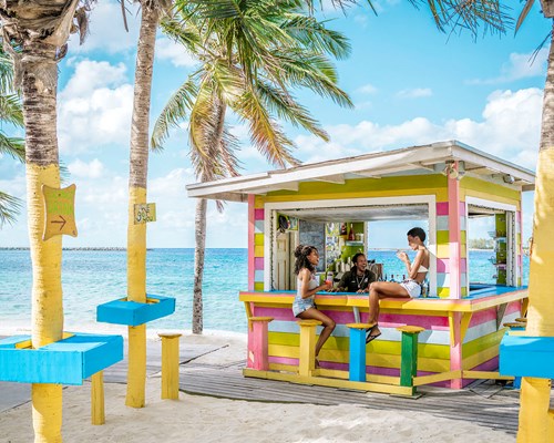 Friends sitting at a colourful beach bar in The Bahamas