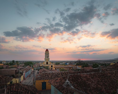 Aerial view of an old city full of charming colourful buildings with terracotta tiled roofs with a pink sunset sky