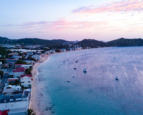 Aerial view of a coastline of a town on a tropical island with purple sunset sky