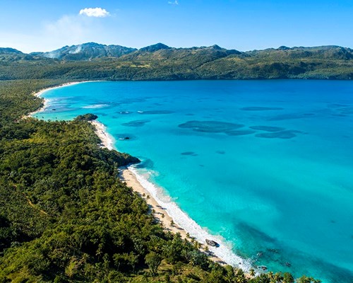  Aerial view of a tropical beach and surrounding forests and mountains 