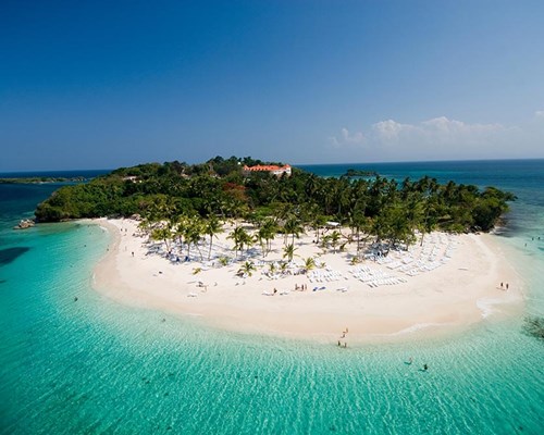 Aerial view of small tropical island with white sand and one large building in the middle of a small forest