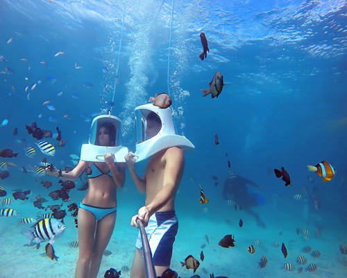 Couple Helmet Diving In Clear Blue Caribbean Sea With Tropical Fish