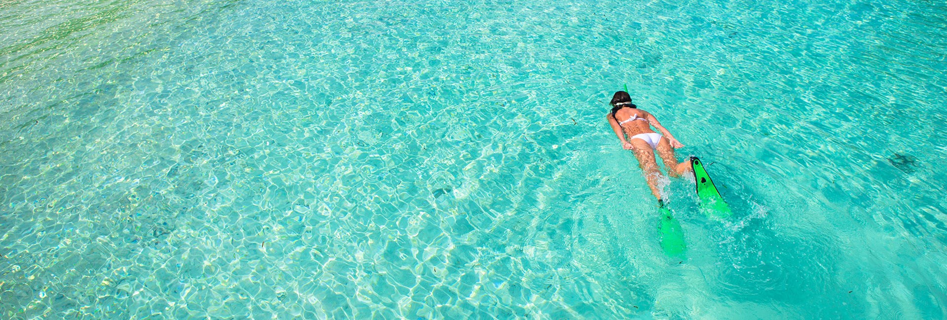 Girl snorkelling in a clear, turquoise tropical sea