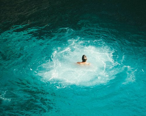 Man swimming in bright blue pool of water 