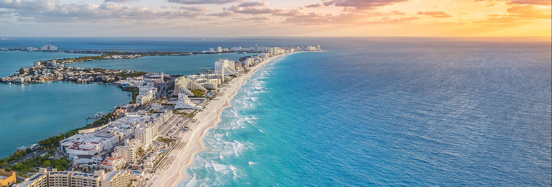 Aerial view of Cancun coast with sun setting over the sea in the distance