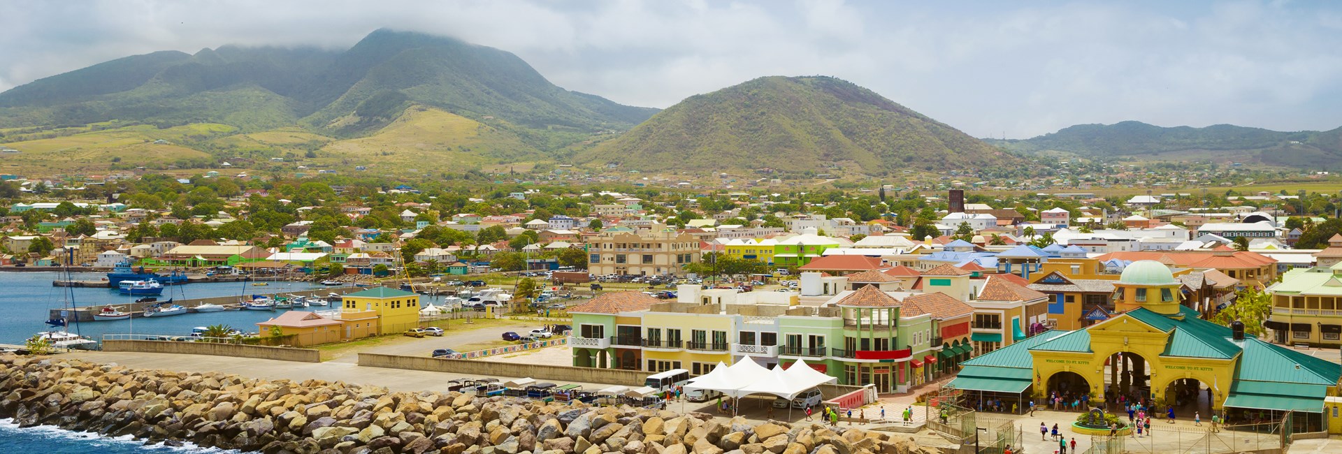 Colourful buildings at a port in a Caribbean town with green hills in the background 