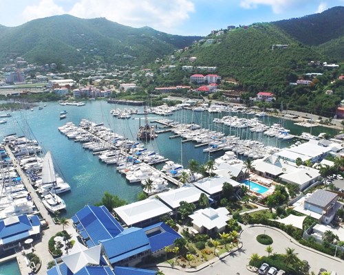 Marina full of boats with colourful buildings and leafy mountains in the background - Soper's Hole, Tortola 