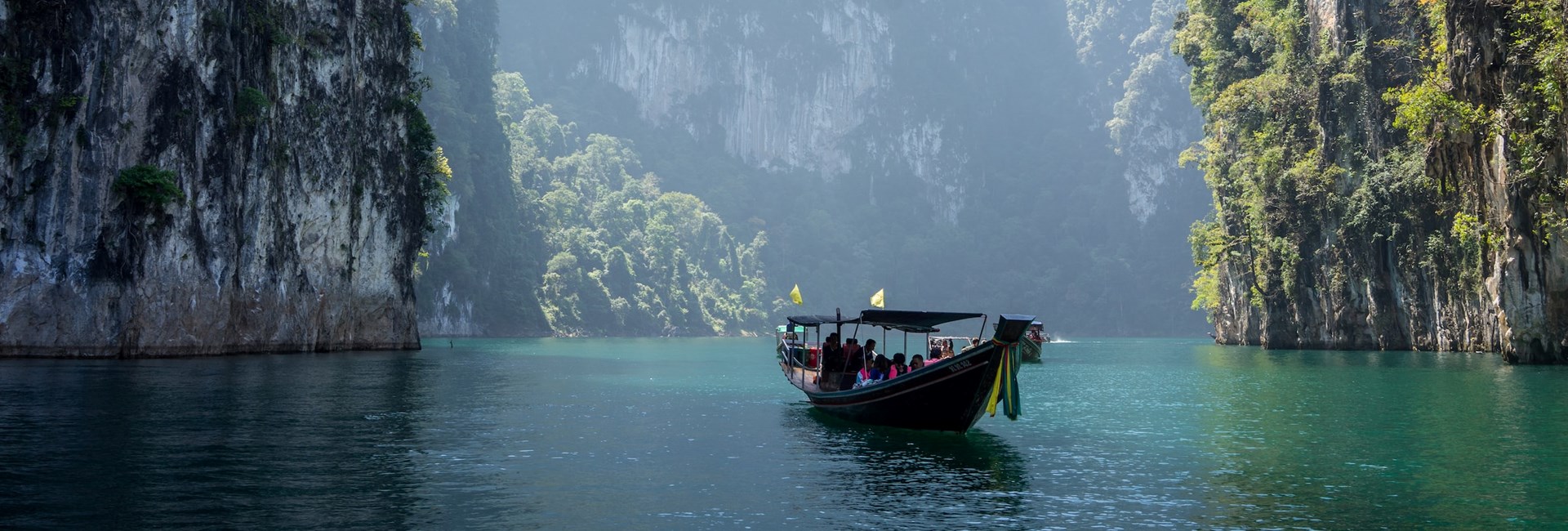 A wooden boat floating on water in between cliffs
