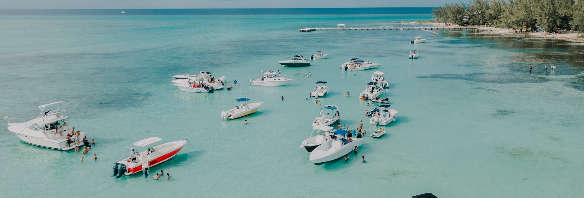 Boats anchored in blue waters with island in background - Cayman Islands 