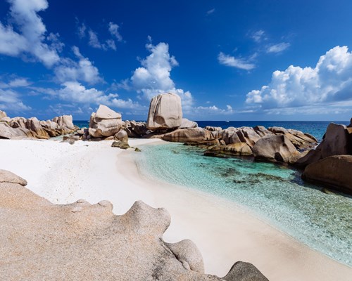 Giant granite boulders surrounding white sandy beach and clear waters - Anse Morran 