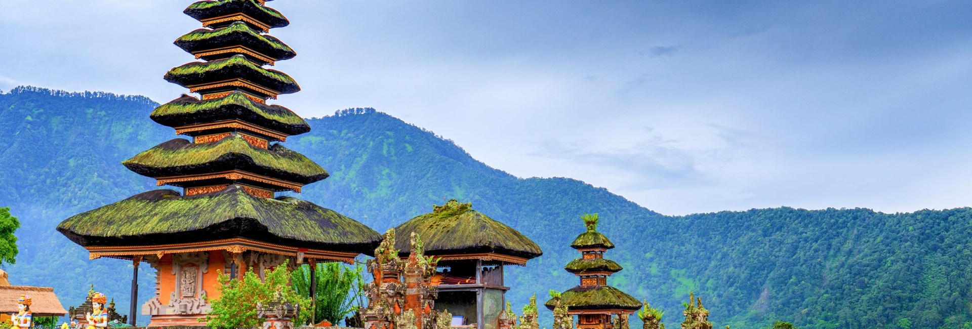 colourful temple in Bali by water with hills in background
