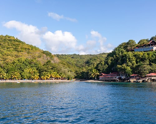 View of tropical dark sand beach barked by forests