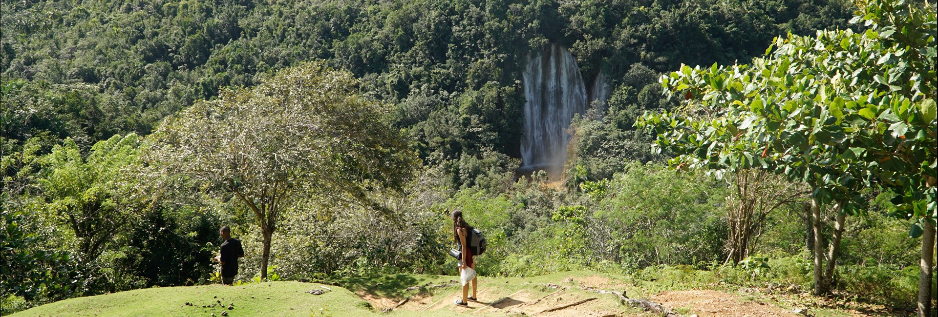  Girl standing on a hill with a tall waterfall in the distance 