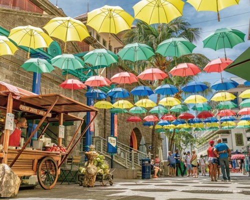 People walking on a market street underneath colourful umbrella's
