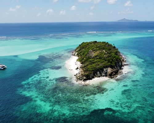 Tiny tropical island surrounded by clear turquoise sea 
