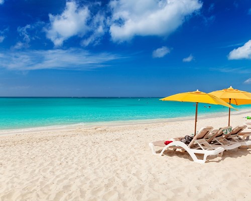 White sun loungers and yellow umbrellas lined up on a white sand beach