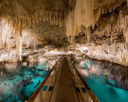 Wooden walkway over a clear pool of blue water in an underground cave