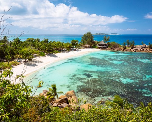 Turquoise waters edging onto to white sand with lush vegetation around the perimeter - Petite Anse Kerlan 
