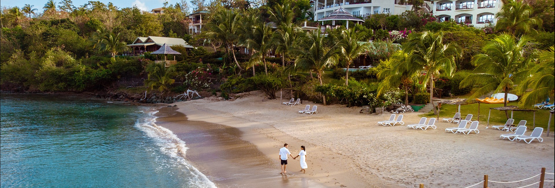 Couple on holiday walking along a beach at the tropical island of St Lucia 