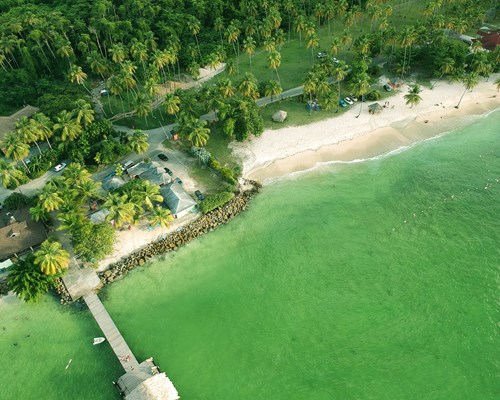 Aerial view of a tropical beach with a pier over clear green water