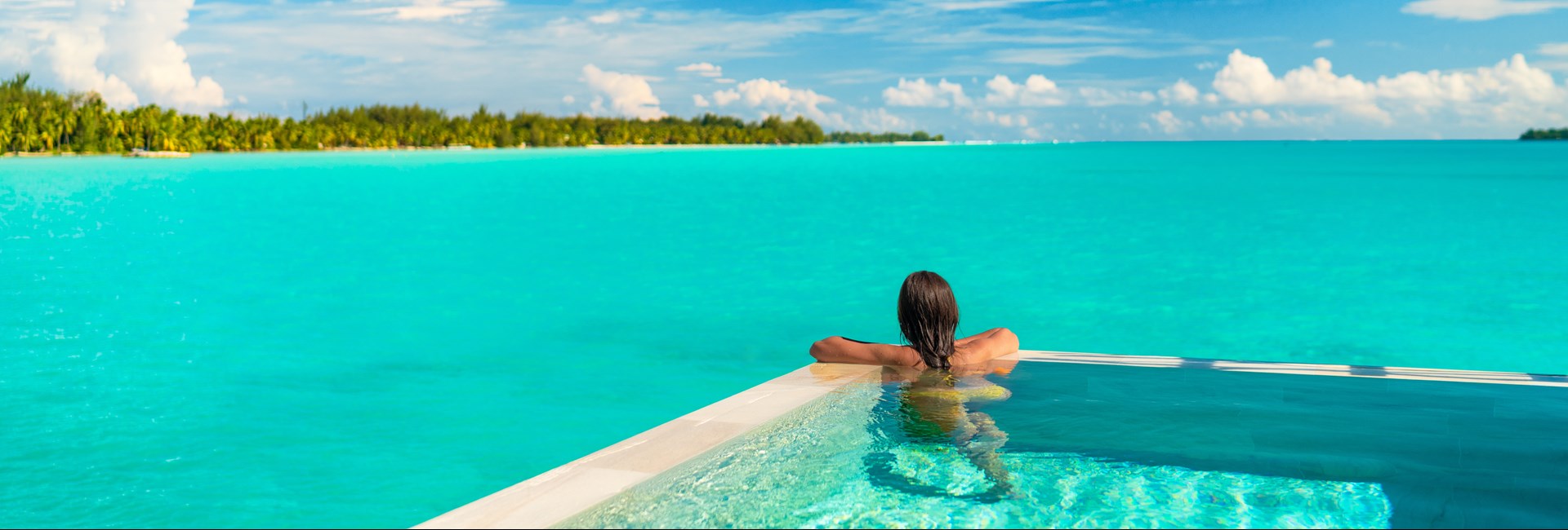 Woman relaxing in infinity pool on luxury beach holiday
