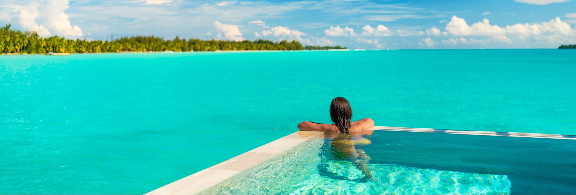 Woman relaxing in infinity pool on luxury beach holiday 