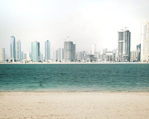 A wide beach with white sands backed by tall buildings