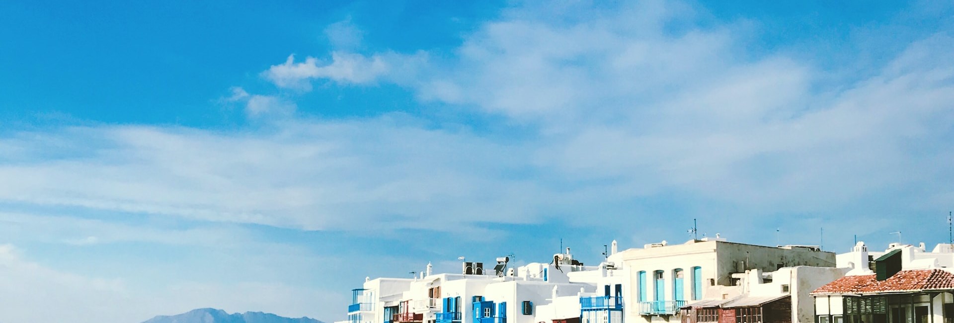 white buildings of Mykonos across blue sea under cobalt sky